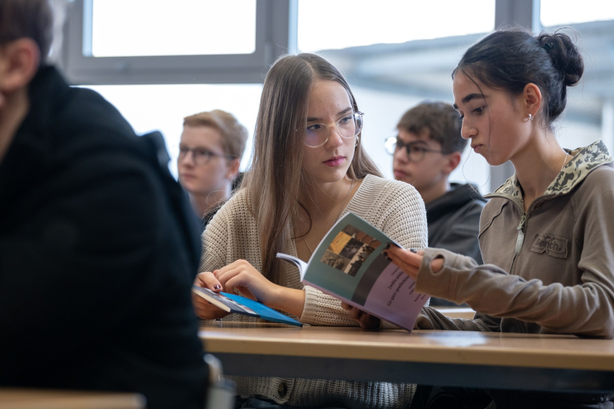 Schülerinnen in Montabaur blättern in einem Buch über Krystyna Kozaks Leben.