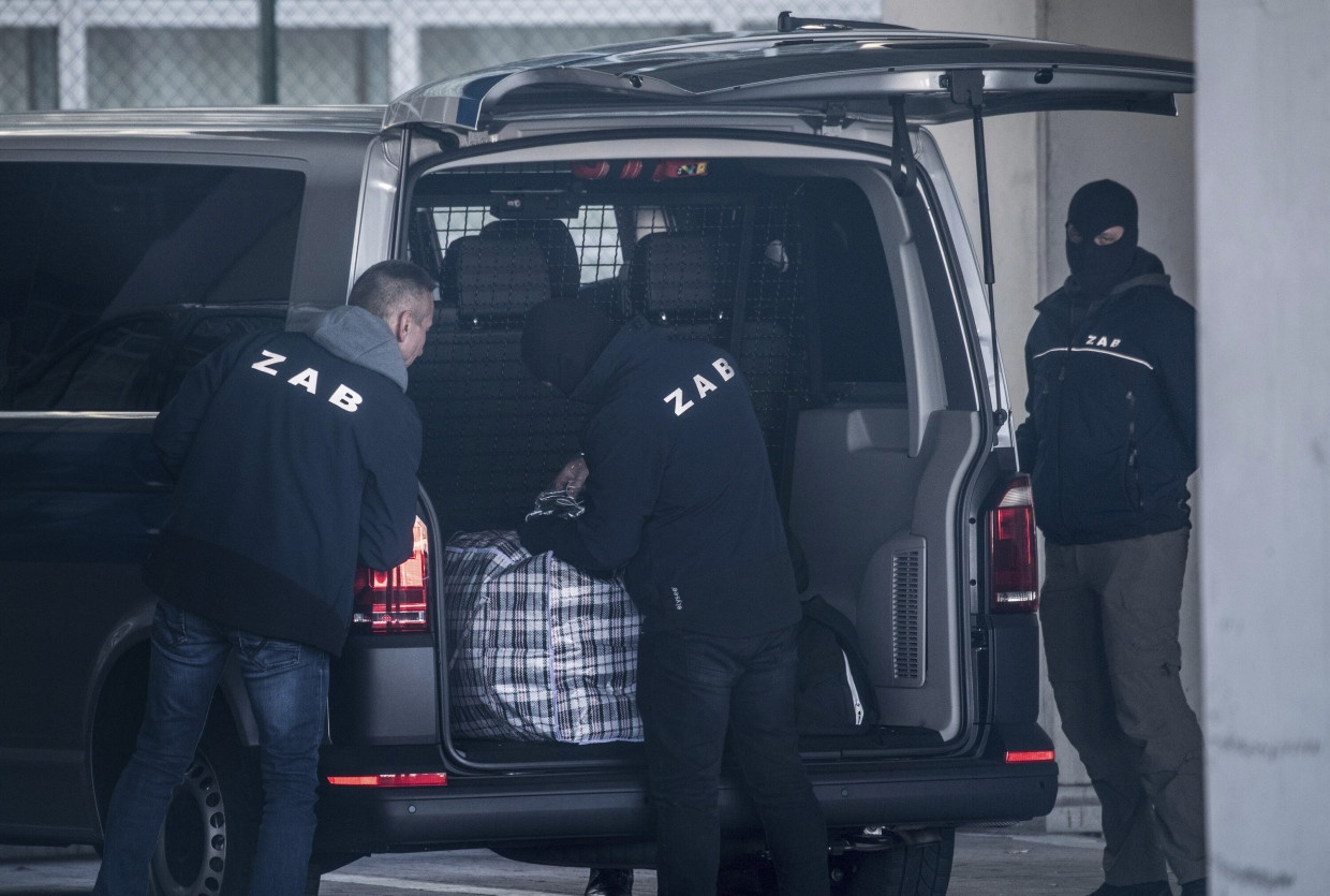 Vermummte Mitarbeiter der Zentralen Ausländerbehörde verladen am Terminal 2 des Frankfurter Flughafens das Gepäck eines Abschiebehäftlings.