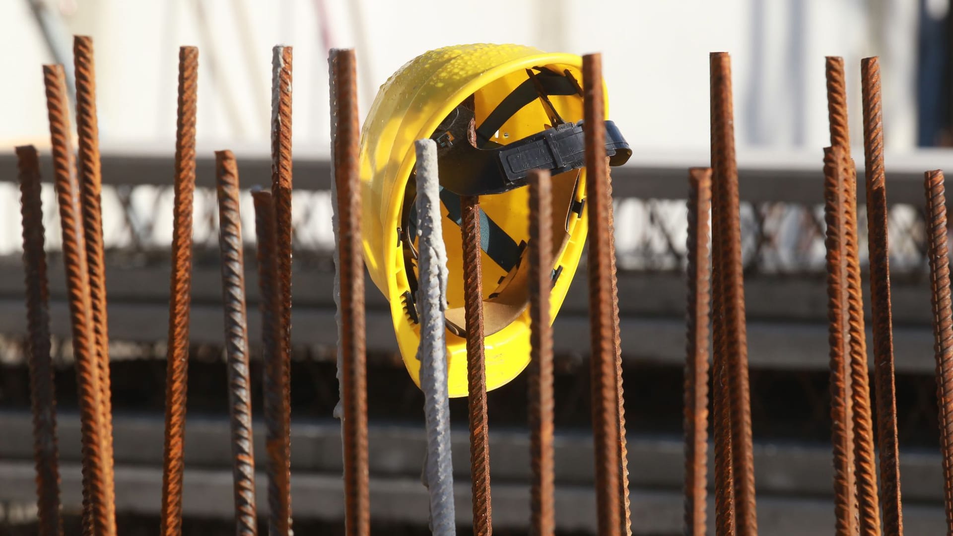 Ein Helm hängt an einer Baustelle (Symbolbild): Auch auf dem Bau wird geeignetes Personal händeringend gesucht.