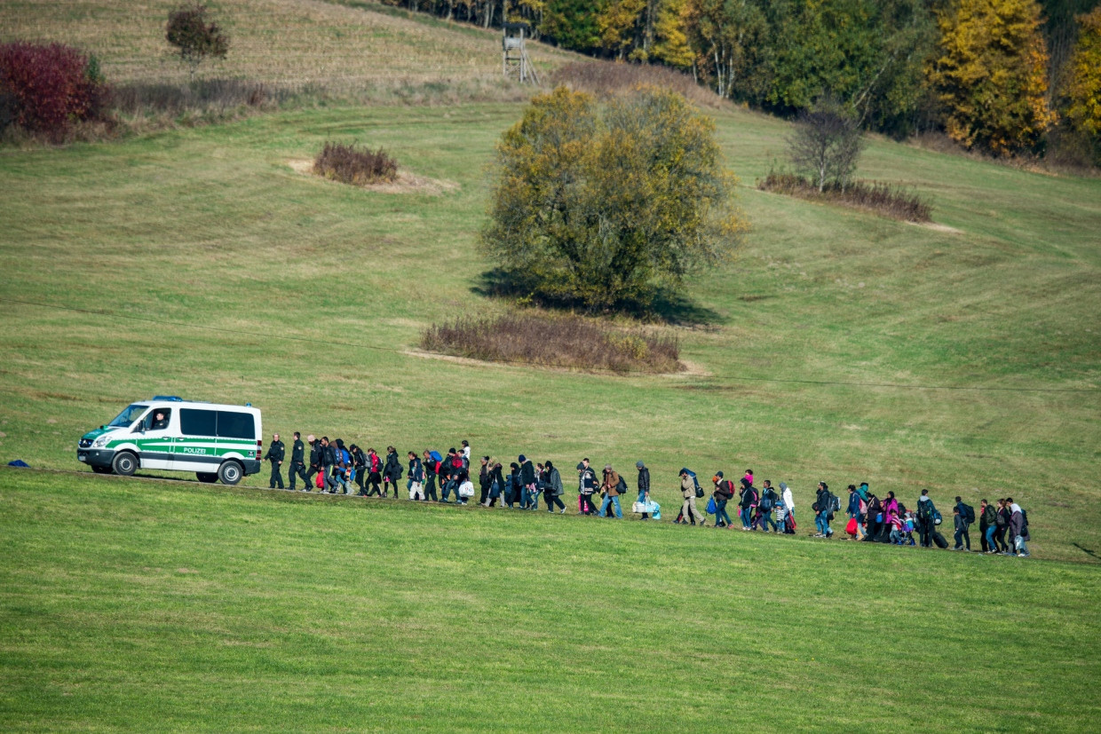 Aufgegriffene Flüchtlinge folgen einem Auto der Bundespolizei in Bayern, das sie zu einer Notunterkunft geleitet.