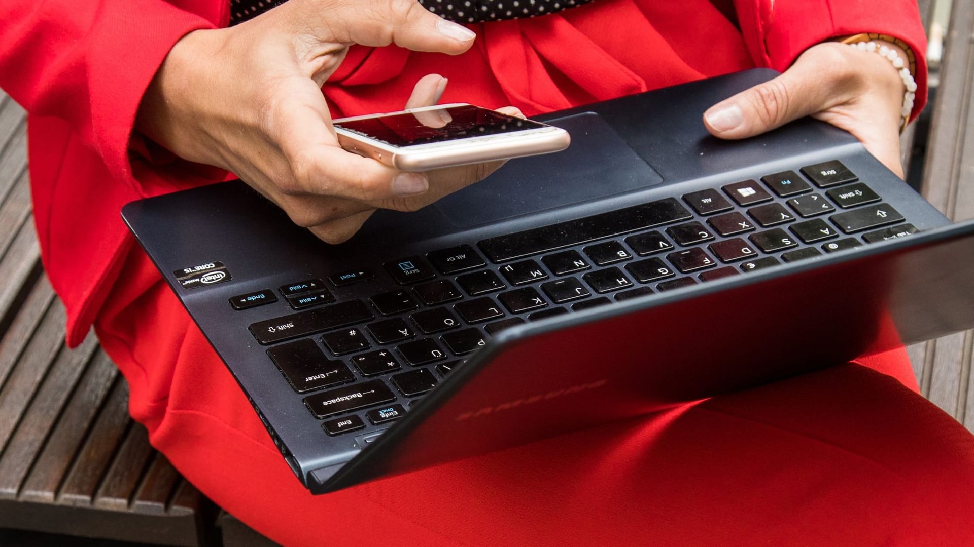 Eine Frau hält ein Smartphone und ein Laptop in den Händen Eine Frau hält ein Smartphone und ein Laptop in den Händen