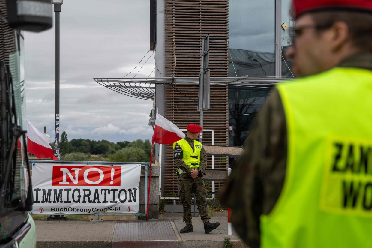 Migranten unerwünscht: Polnische Grenzer stehen vor einem Transparent der „Bürgerwehr“