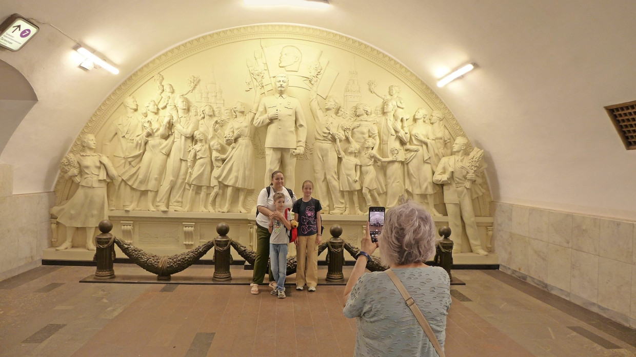 Passanten posieren vor dem Stalin-Denkmal in der U-Bahn-Station Taganskaja.