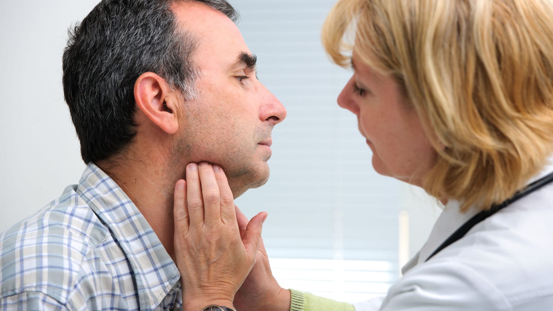 Ärztin tastet die Lymphknoten am Hals eines Patienten ab. Ärztin tastet die Lymphknoten am Hals eines Patienten ab.