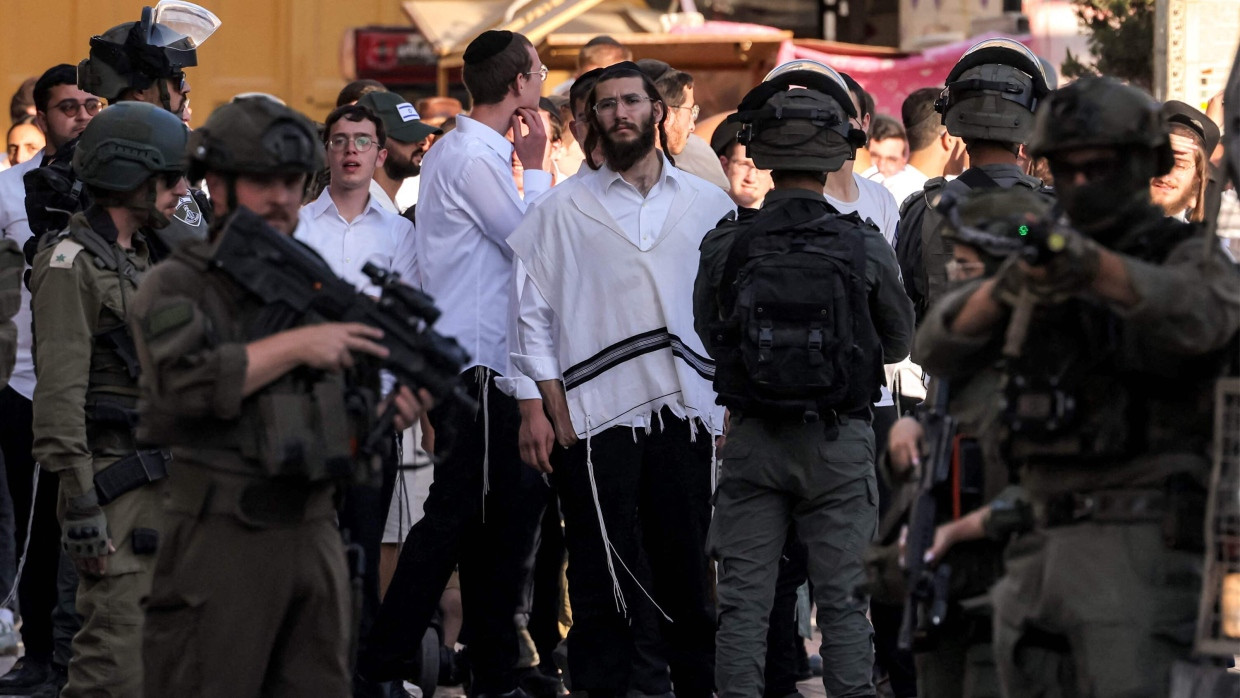 Israelische Soldaten stehen Wache, während israelische Siedler am 28. Juni 2025 die Altstadt der palästinensischen Stadt Hebron im Westjordanland besichtigen.