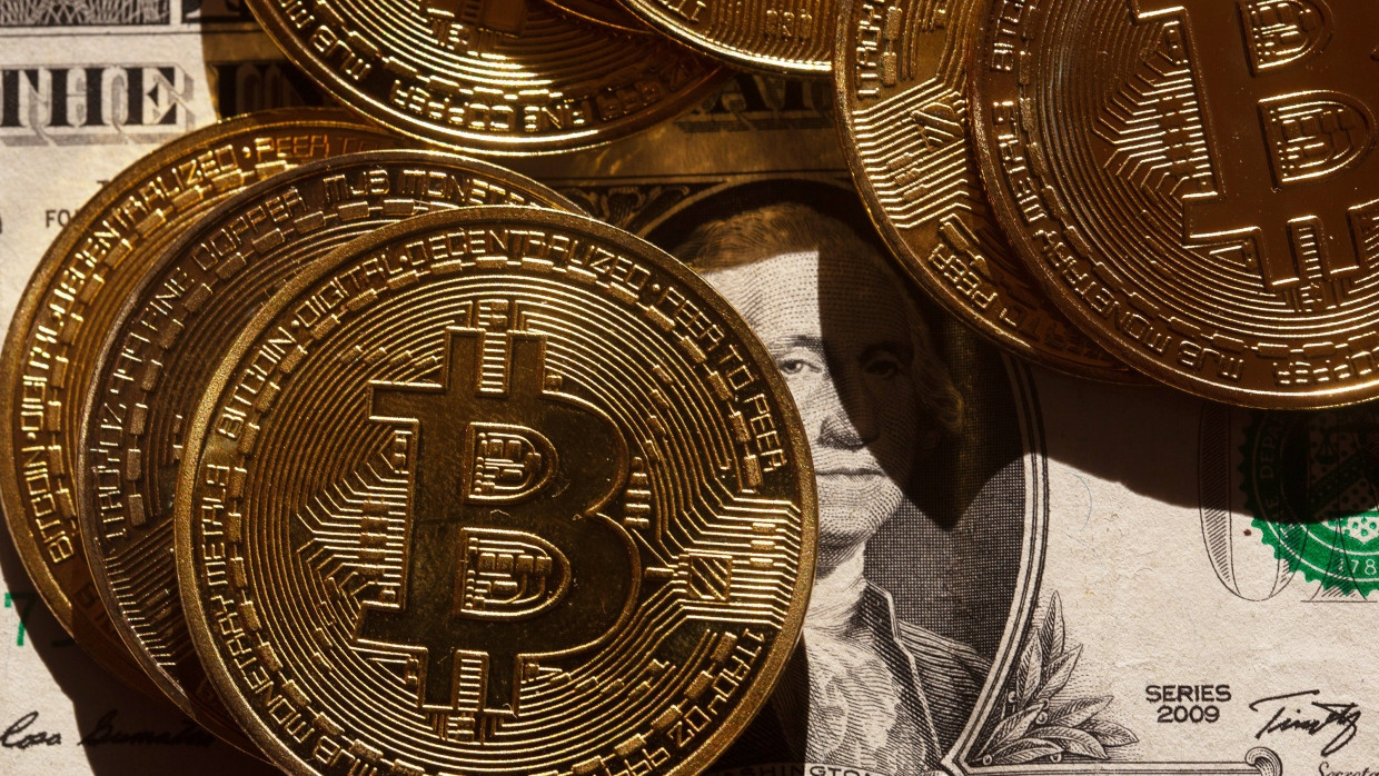 Goldene Bitcoin-Münzen liegen auf einer US-Dollar-Banknote in Berlin.