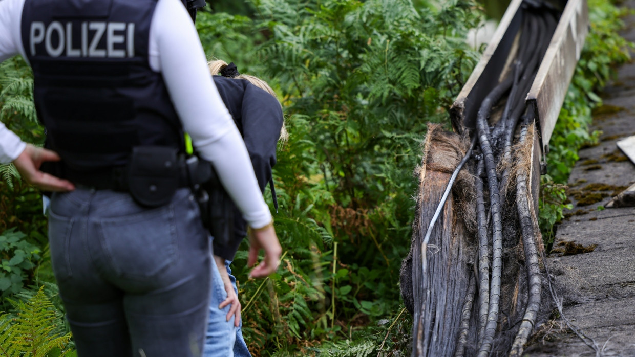 Polizeibeamte der Spurensicherung stehen in Düsseldorf an einem Gleisabschnitt. Dort wurde neben der Bahnstrecke Feuer in einem Kabeltunnel gelegt.