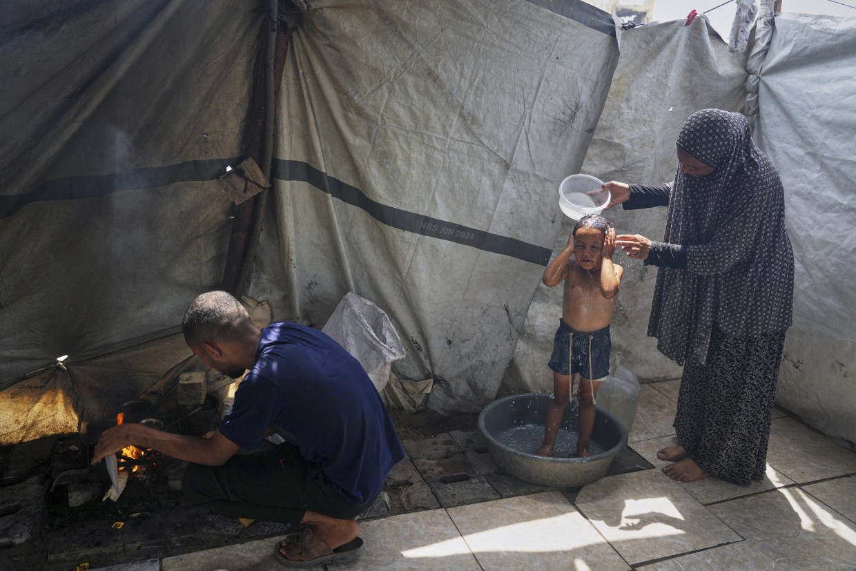 Eine palästinensische Großmutter wäscht ihr Enkelkind in einer Flüchtlingsunterkunft in Gaza-Stadt, am 12.8.2025.