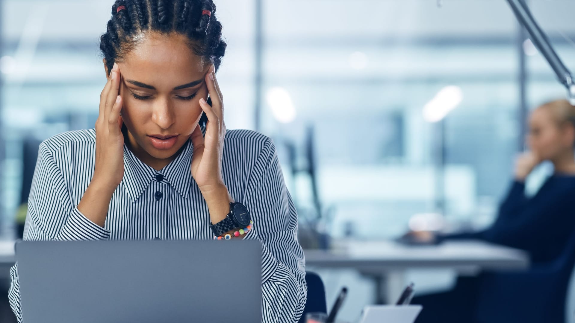 Frau im Büro massiert sich die Schläfen Frau im Büro massiert sich die Schläfen